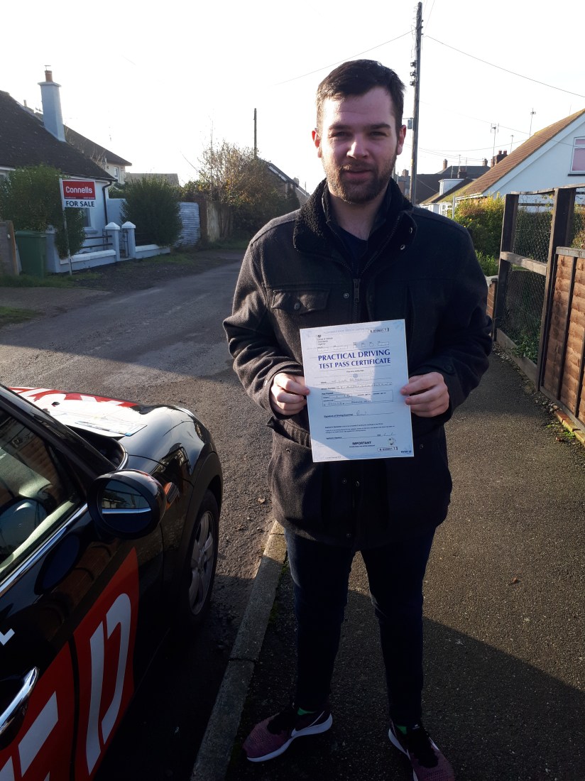 Man holding test pass certificate by car